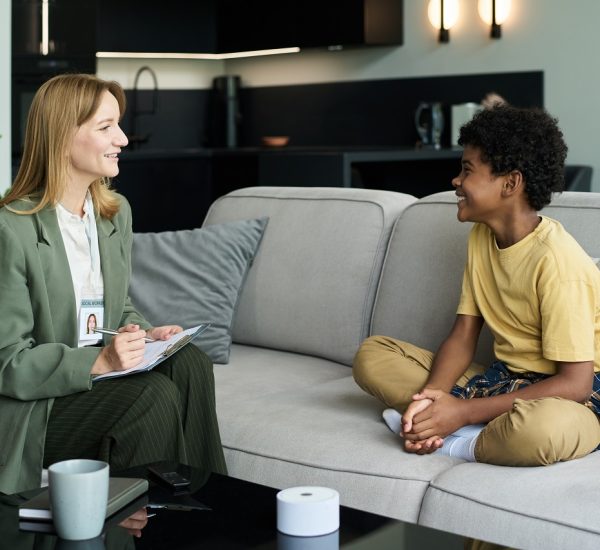 Smiling Therapist Engaging with Happy Young Patient Therapist sitting on couch in modern office engaging with young patient. Couch in foreground with office setting in background, promoting mental health care